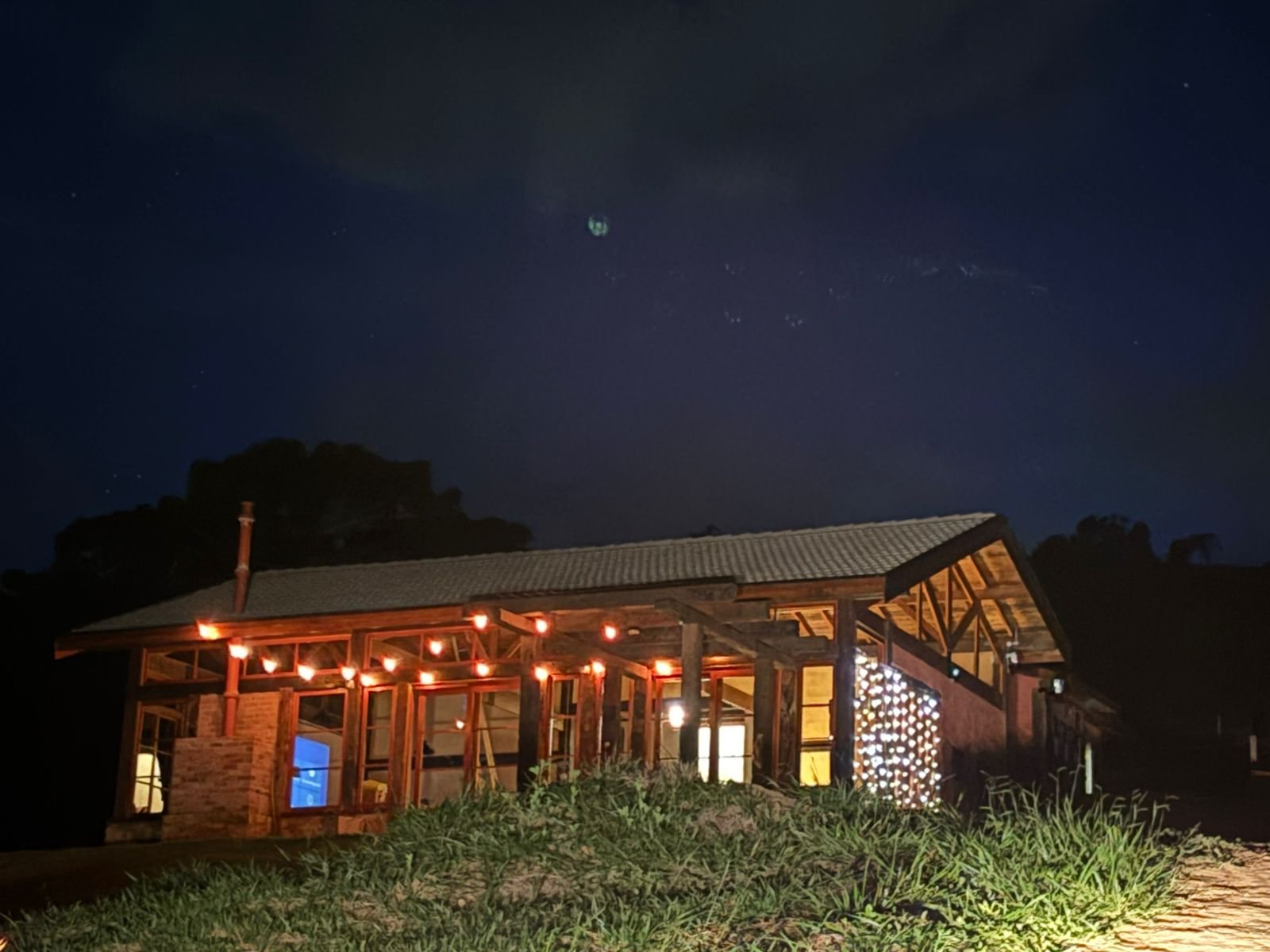 A casa iluminada à noite, com as luzes do vale ao fundo