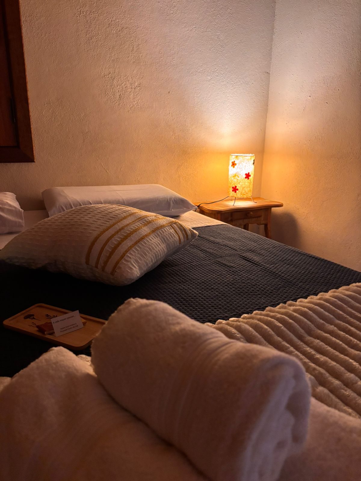 Enxoval preparado na cama da Suíte Cedro, à luz do abajur