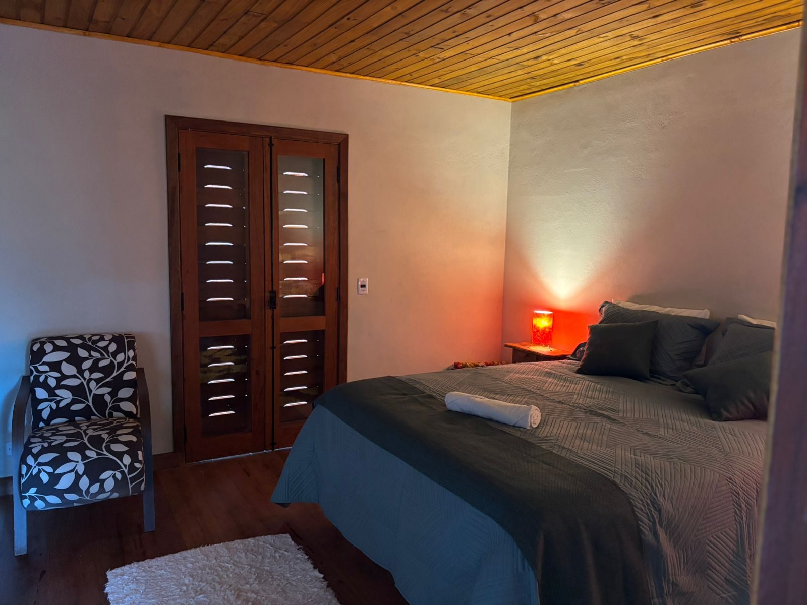 Cama da Suíte Cedro, ao lado da porta de madeira