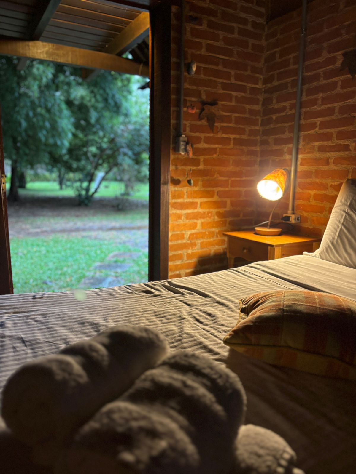 Toalhas sobre a cama e a porta aberta para o gramado