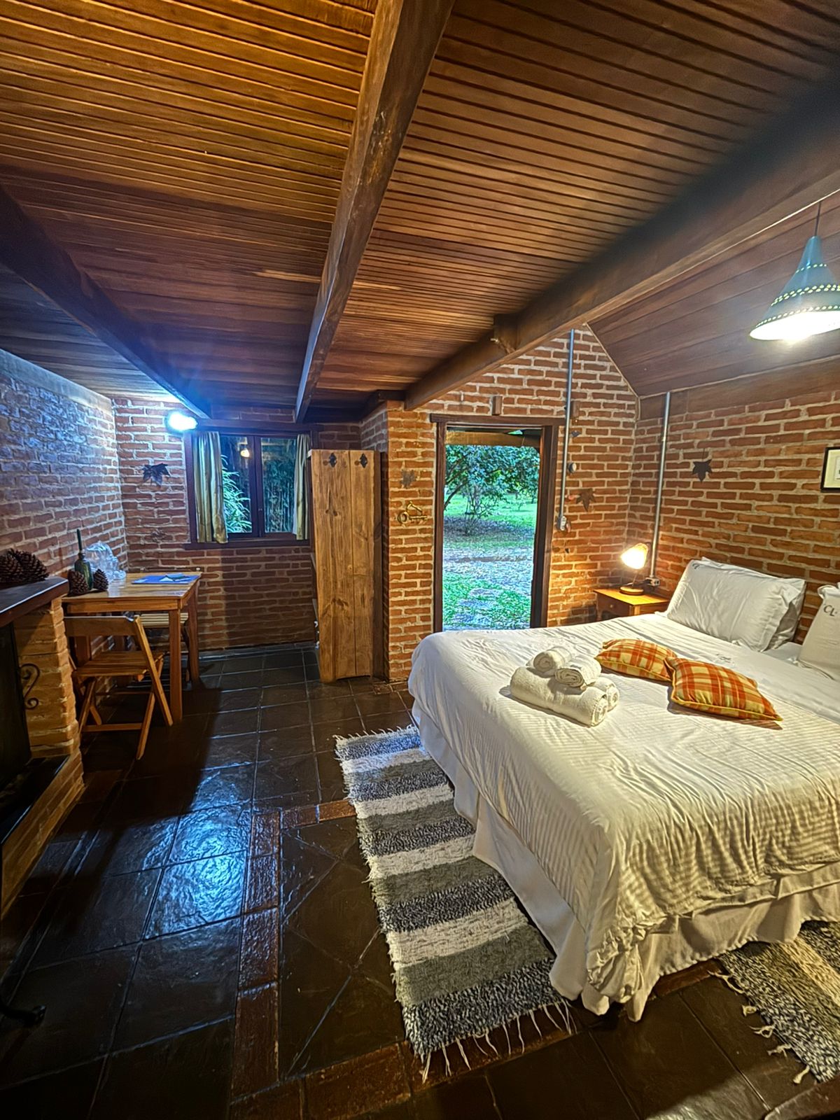 Quarto com mesa, armário de madeira e cama arrumada