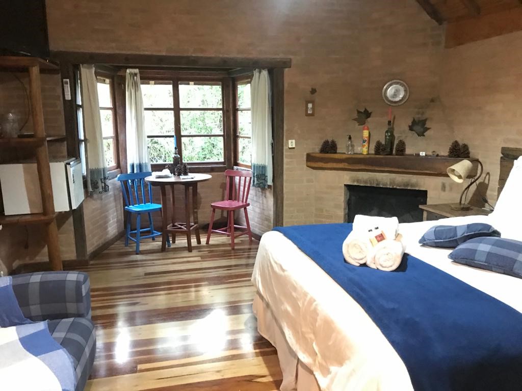 Quarto com sofá xadrez, piso de madeira e lareira