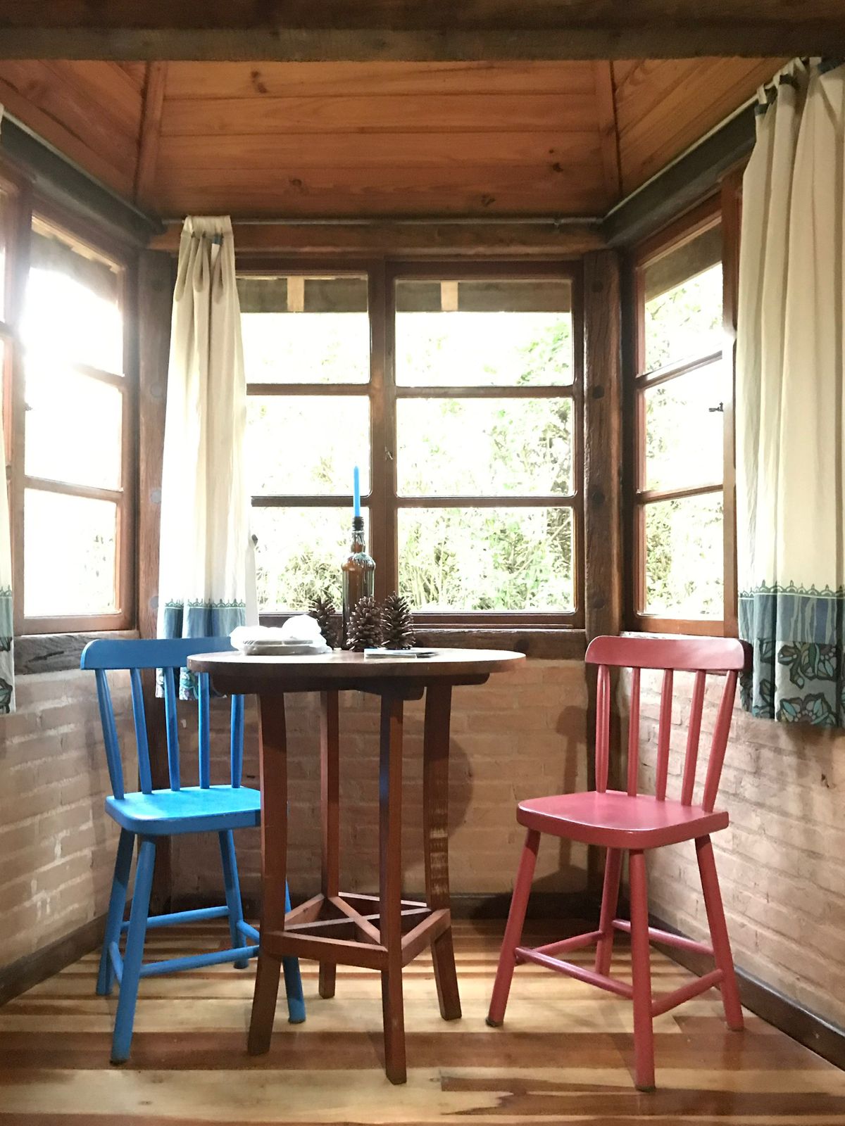 Cadeiras azul e vermelha na bay window do chalé