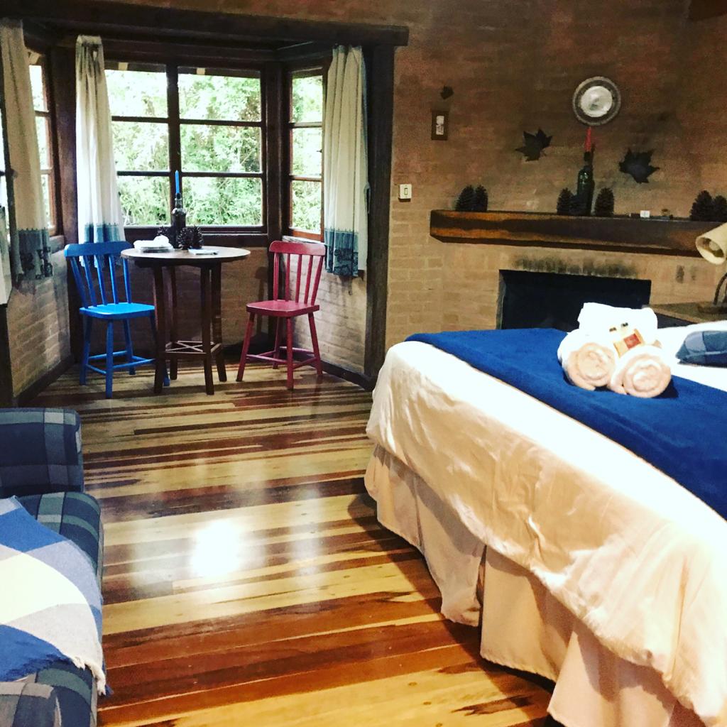 Quarto do Eucalipto com a mesa junto à janela e as cadeiras azul e vermelha