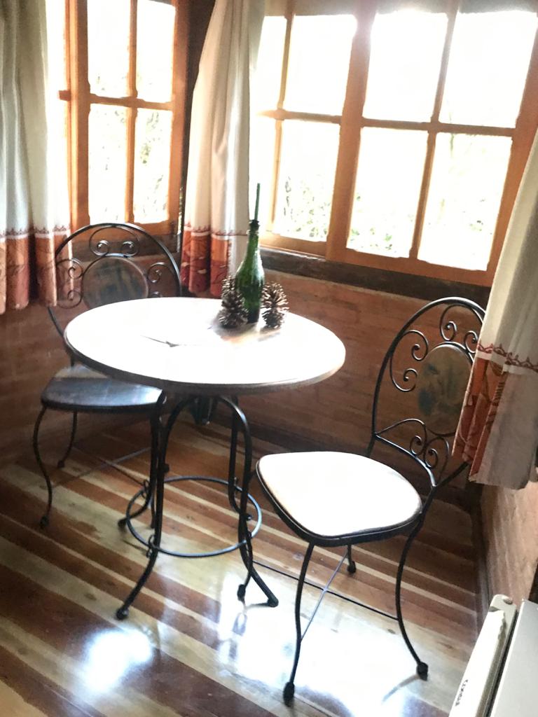 Mesa de ferro com garrafa e pinhas junto à janela