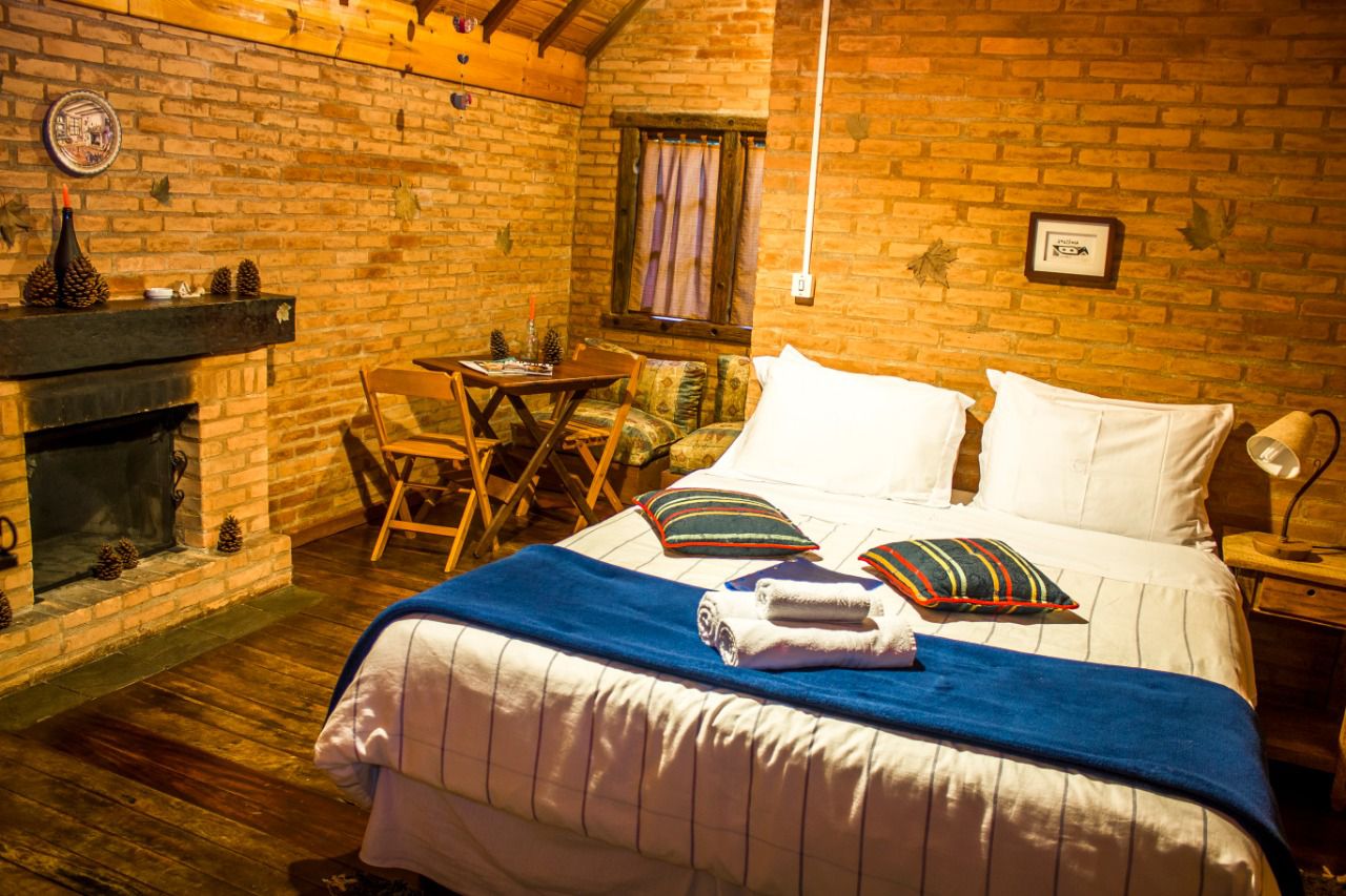 Chalé Ipê: quarto com lareira e mesa junto à janela