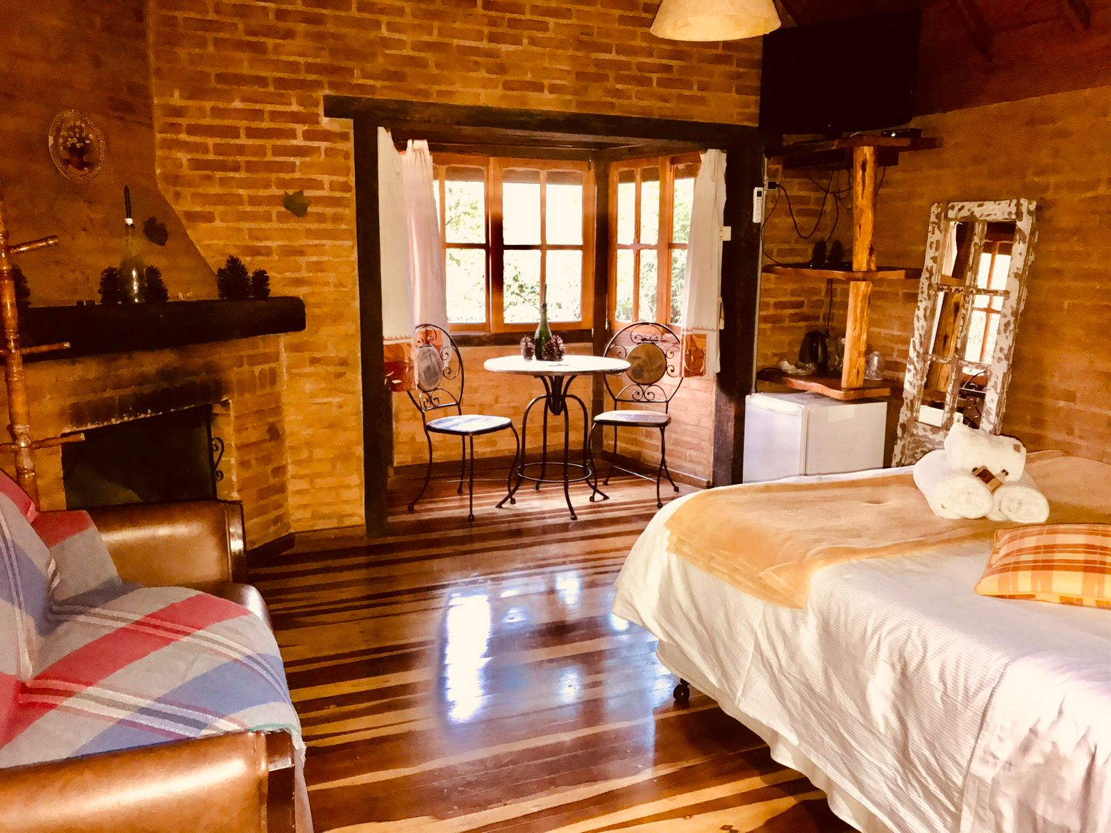 Sala do Manacá com sofá, lareira, mesa e cama