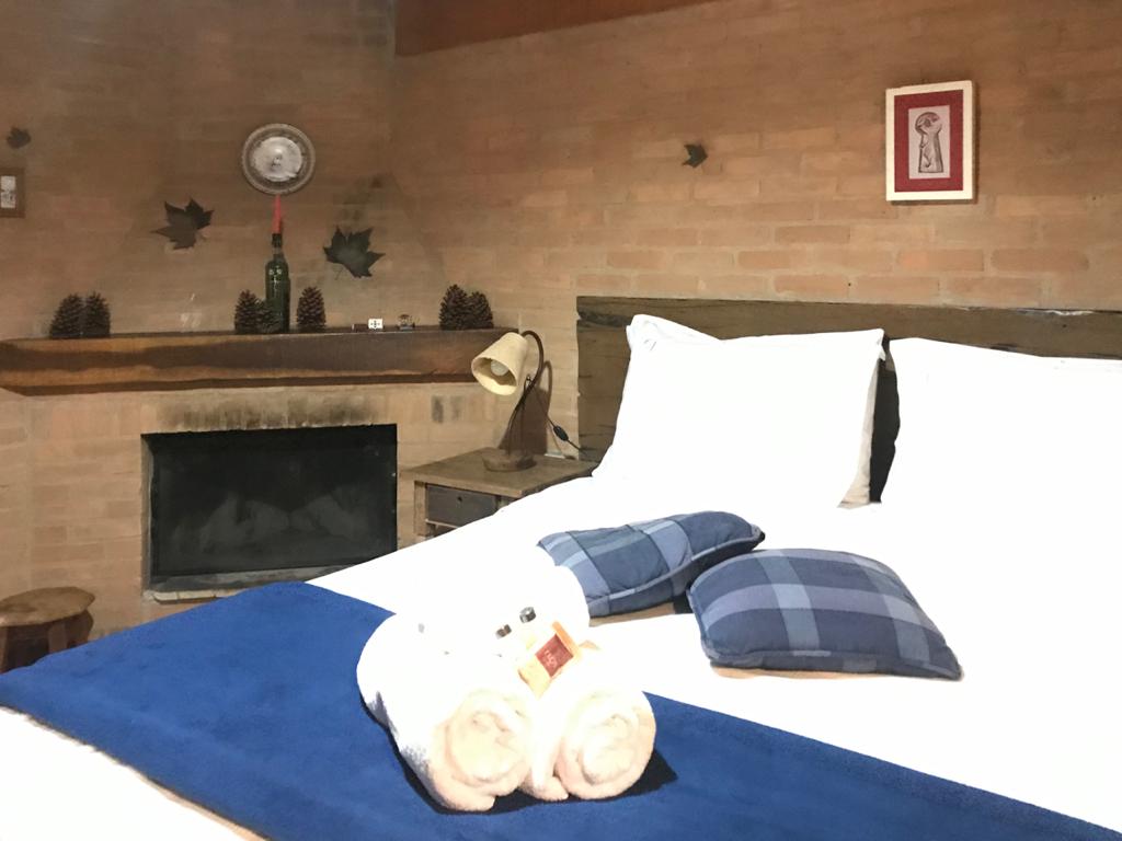 Cama com toalhas e almofadas azuis, lareira ao lado