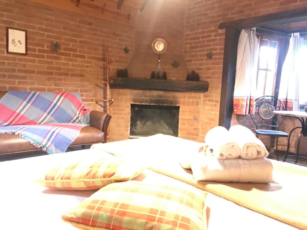 Almofadas xadrez sobre a cama e a lareira ao fundo