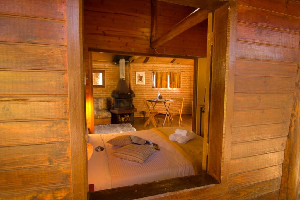 Cama vista pela janela de madeira, com a sala ao fundo