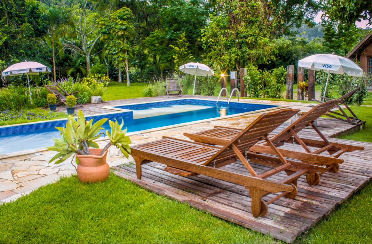 Piscina climatizada com deck de madeira e espreguiçadeiras no jardim
