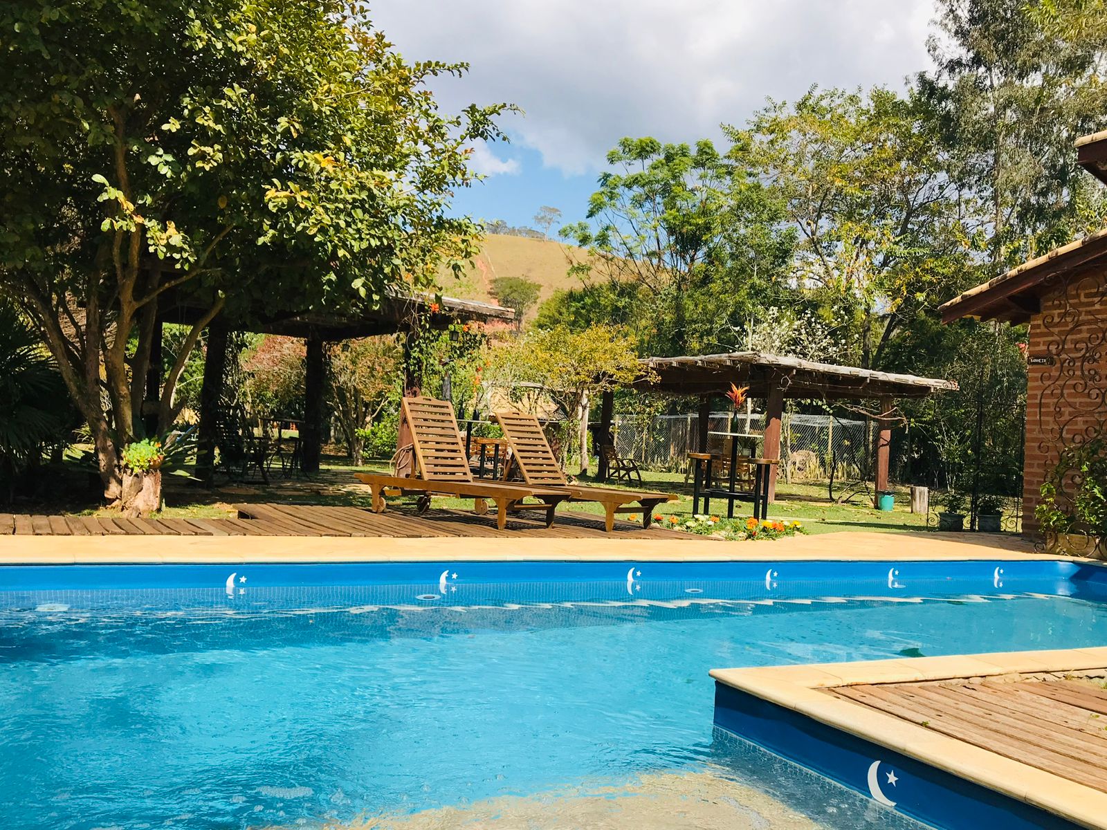 Piscina e deck de madeira com a serra ao fundo